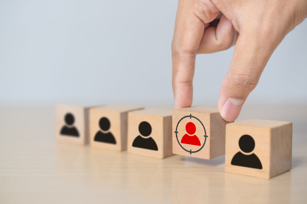 Hand moving a wooden block with a targeted person icon, symbolizing discrimination mediation.