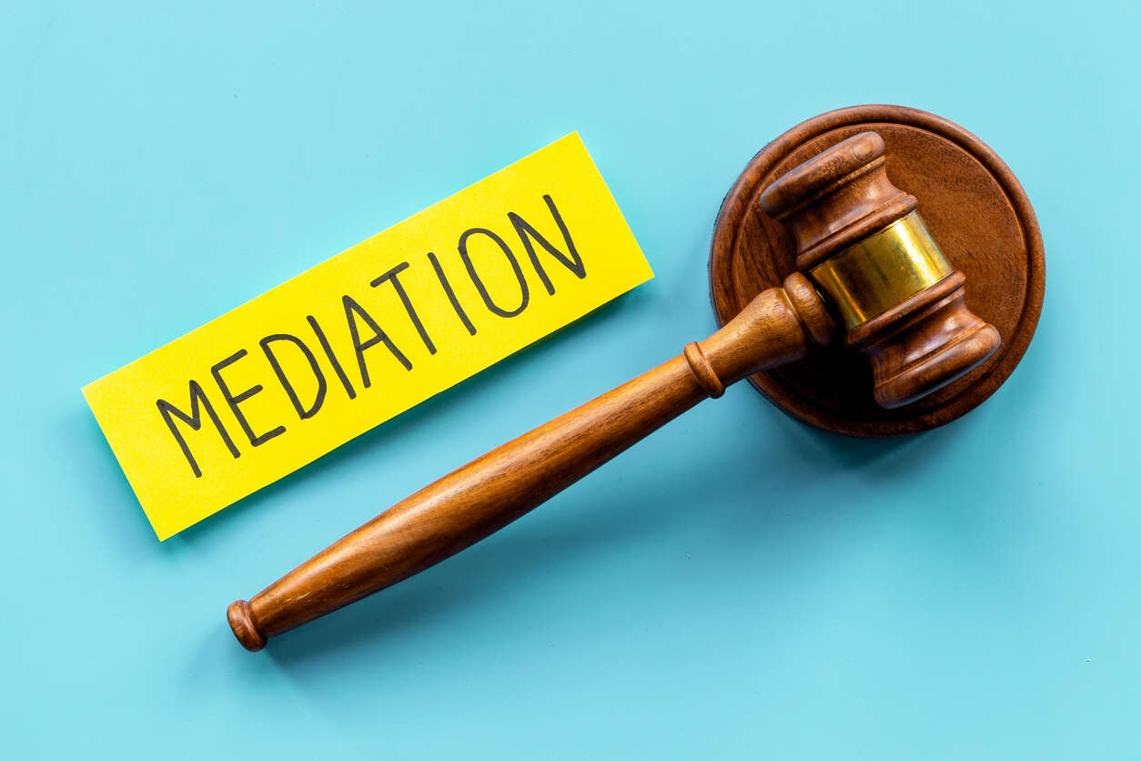 A wooden gavel placed next to a yellow sticky note with the word "MEDIATION" written on it, symbolizing the concept of PAGA mediation and its potential benefits.